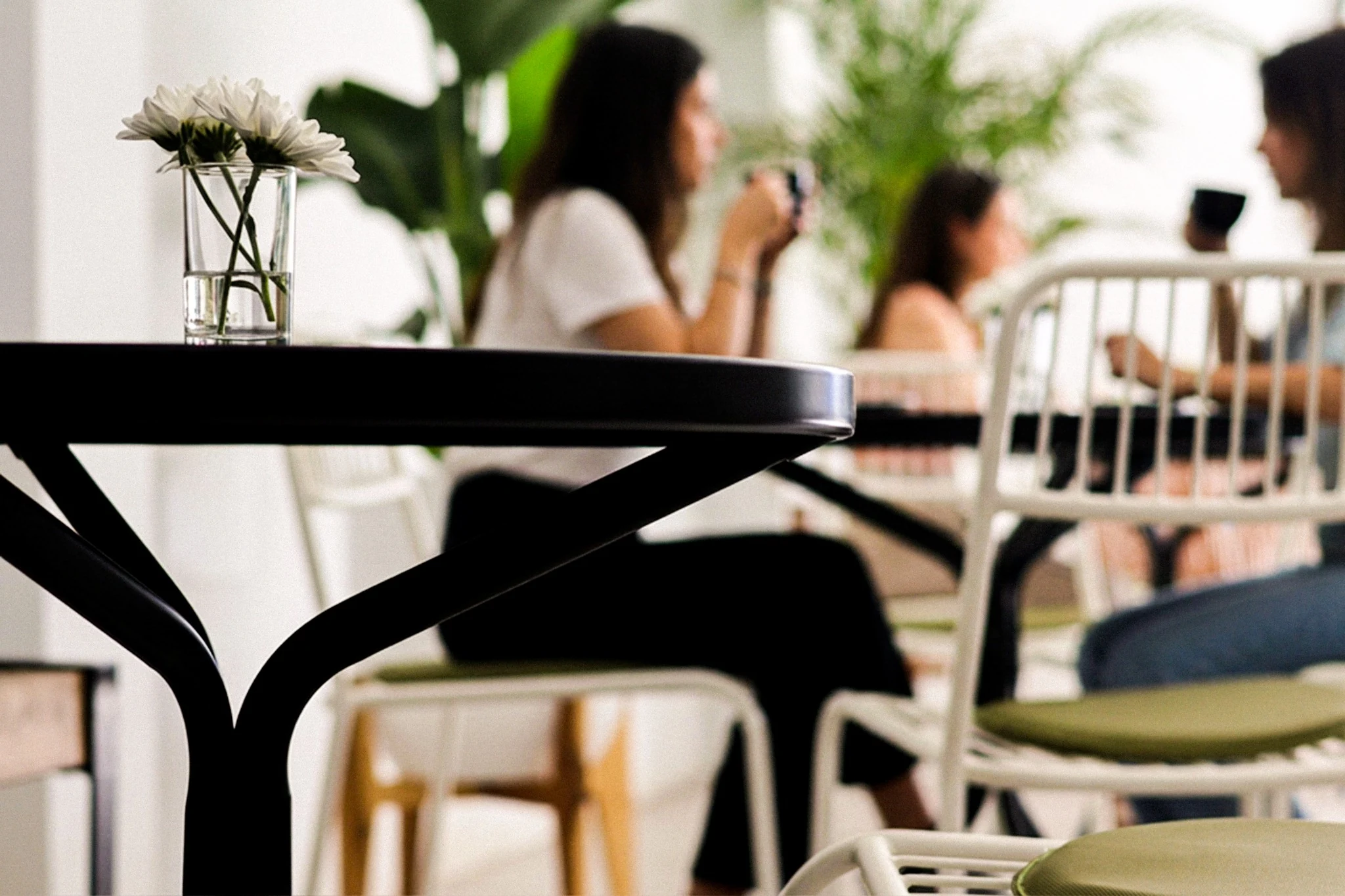 Tavolo e fiore a fuoco, con persone che condividono un caffè sullo sfondo.
